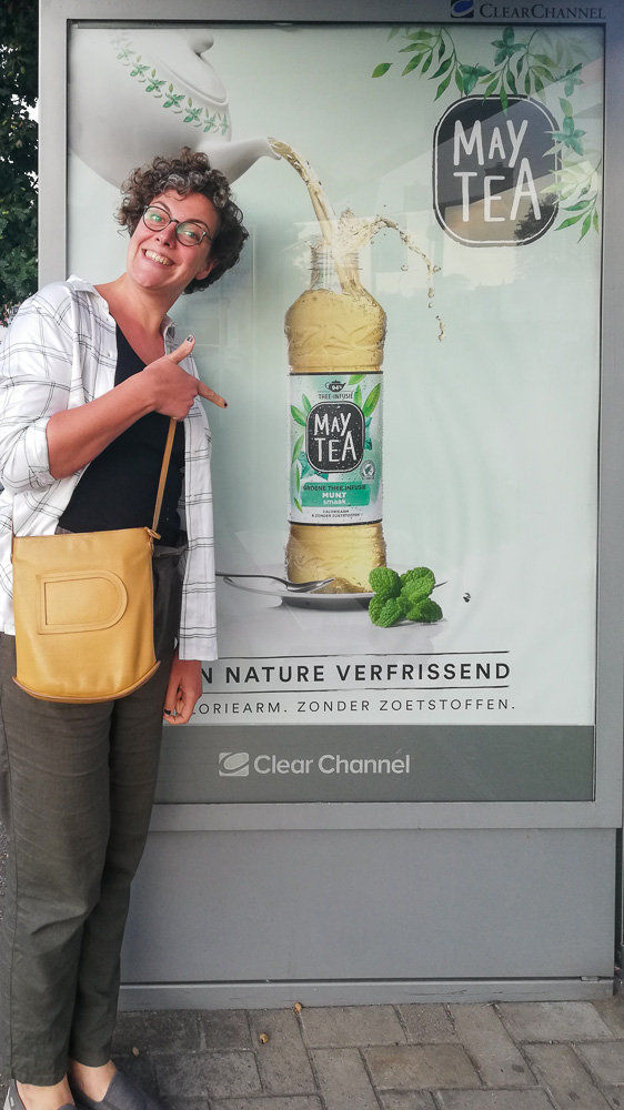 Eveline Boone in front of a billboard with May Tea advertising pointing at her food styling work