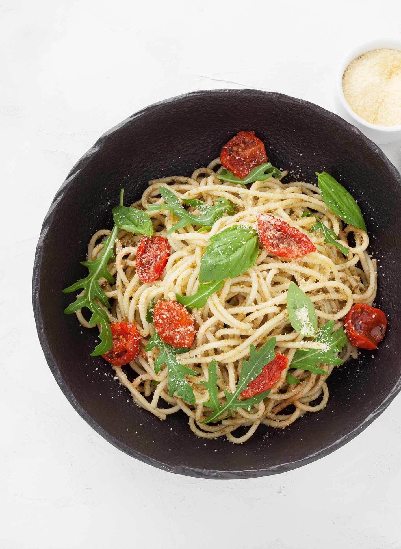 spahgetti with dried tomatoes basil and parmigiana in a black bowl in a restaurant