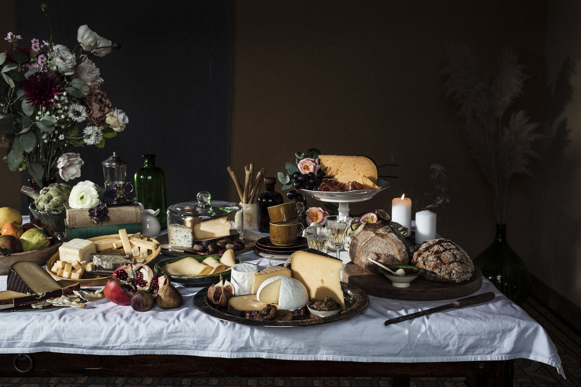 still life with cheese flowers fruits and nuts on a white table cloth
