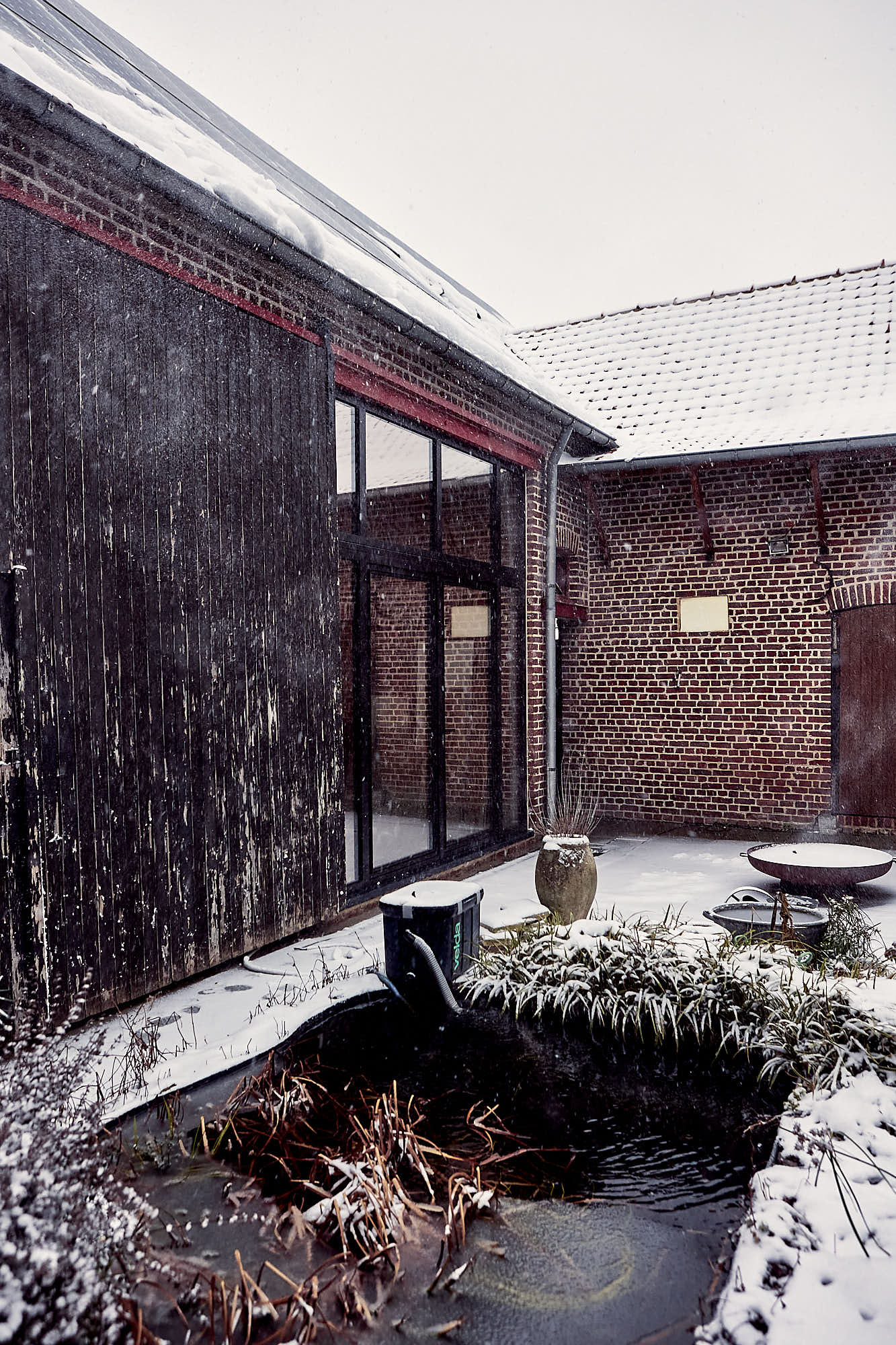 courtyard and pond with a farm surrounding it in the snow